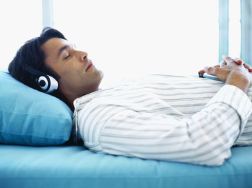 Person using binaural beats to sleep in bed with headphones